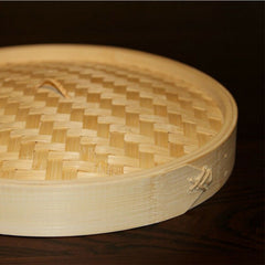 Bamboo steamer basket with lid on a dark background